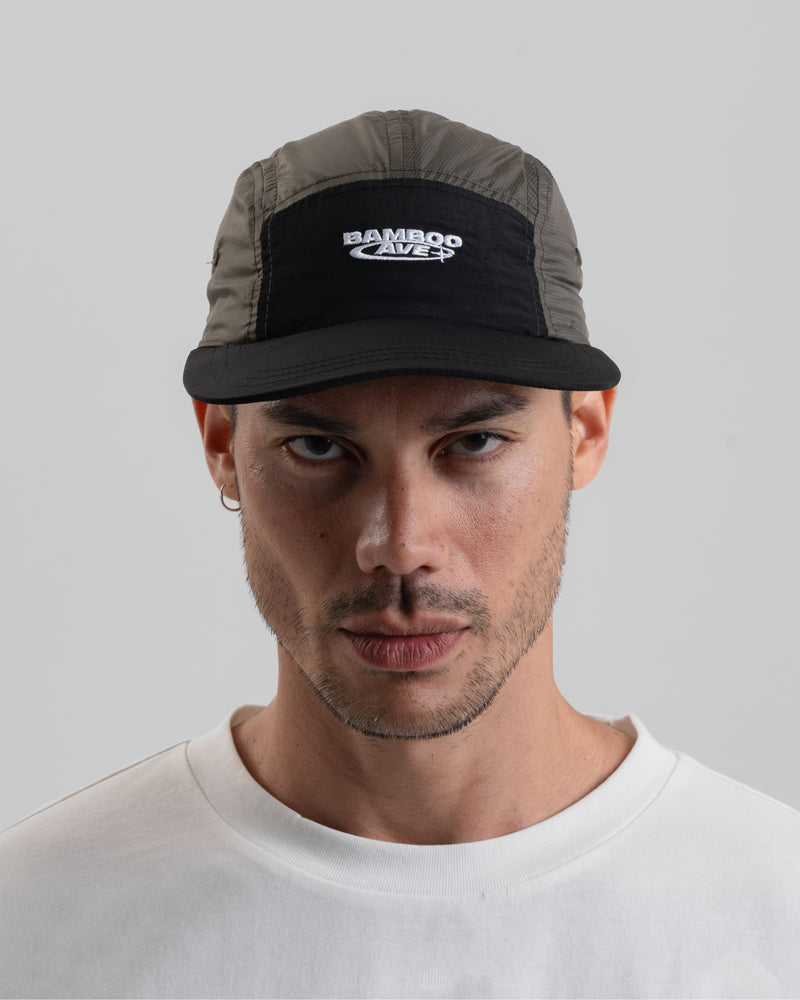 A person wearing a lightweight, two-tone cap in gray and black with a logo on the front - Bamboo Ave